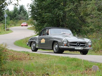 Ein dunkelgrauer Oldtimer fährt auf einer Landstraße