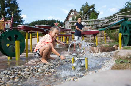 [Translate to english:] Ein Mädchen und ein Junge spielen am Wasserspielplatz im Luxushotel Schwarzwald