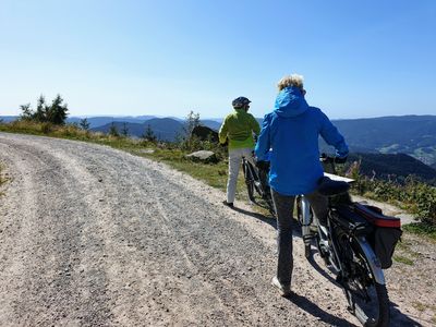 Zwei Fahrradfahrer stehen am Rand eines Schotterweges und genießen die Aussicht 