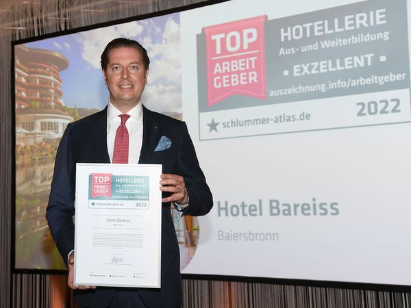 Hannes Bareiss posiert mit einem Preis der Top Arbeitgeber aus der Hotellerie 2022