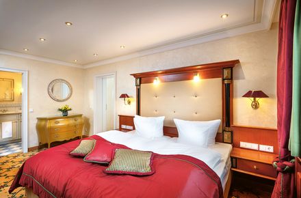 Schlafzimmer des Familienappartements im Hotel Bareiss mit edlen Mahagonimöbeln und roten Akzenten