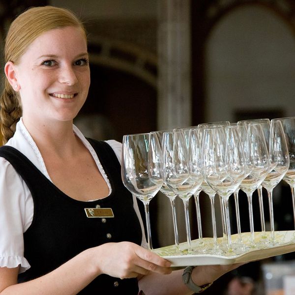 Eine Frau trägt viele Champagnergläser auf einem Tablett