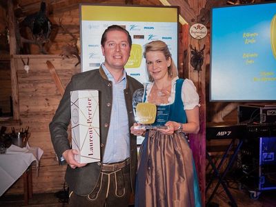 Hannes und Britta Bareiss posieren mit einer Flasche Champagner und dem Family Cup 2022