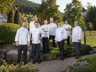Teamfoto der Küchenbrigade in ihrer Arbeitskleidung im Garten des Hotels