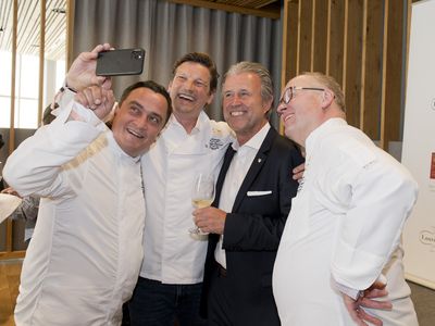Claus-Peter Lumpp macht ein Handy-Foto mit zwei anderen Köchen und einem Herrn im Anzug