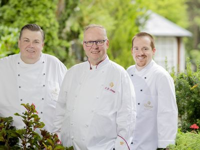 Claus-Peter Lumpp und zwei weitere Köche stehen im Garten des Hotel Bareiss
