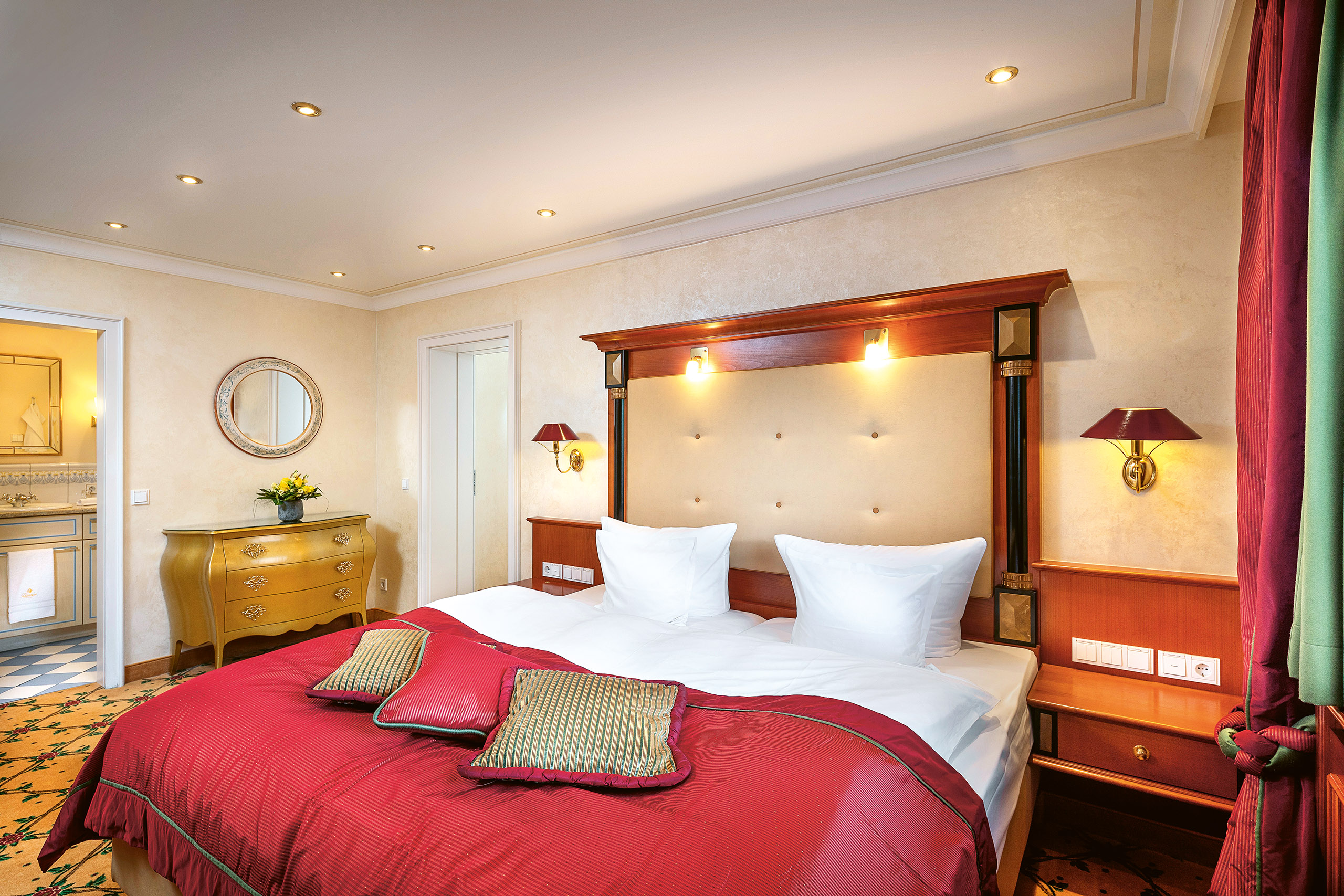 Schlafzimmer des Familienappartements im Hotel Bareiss mit edlen Mahagonimöbeln und roten Akzenten