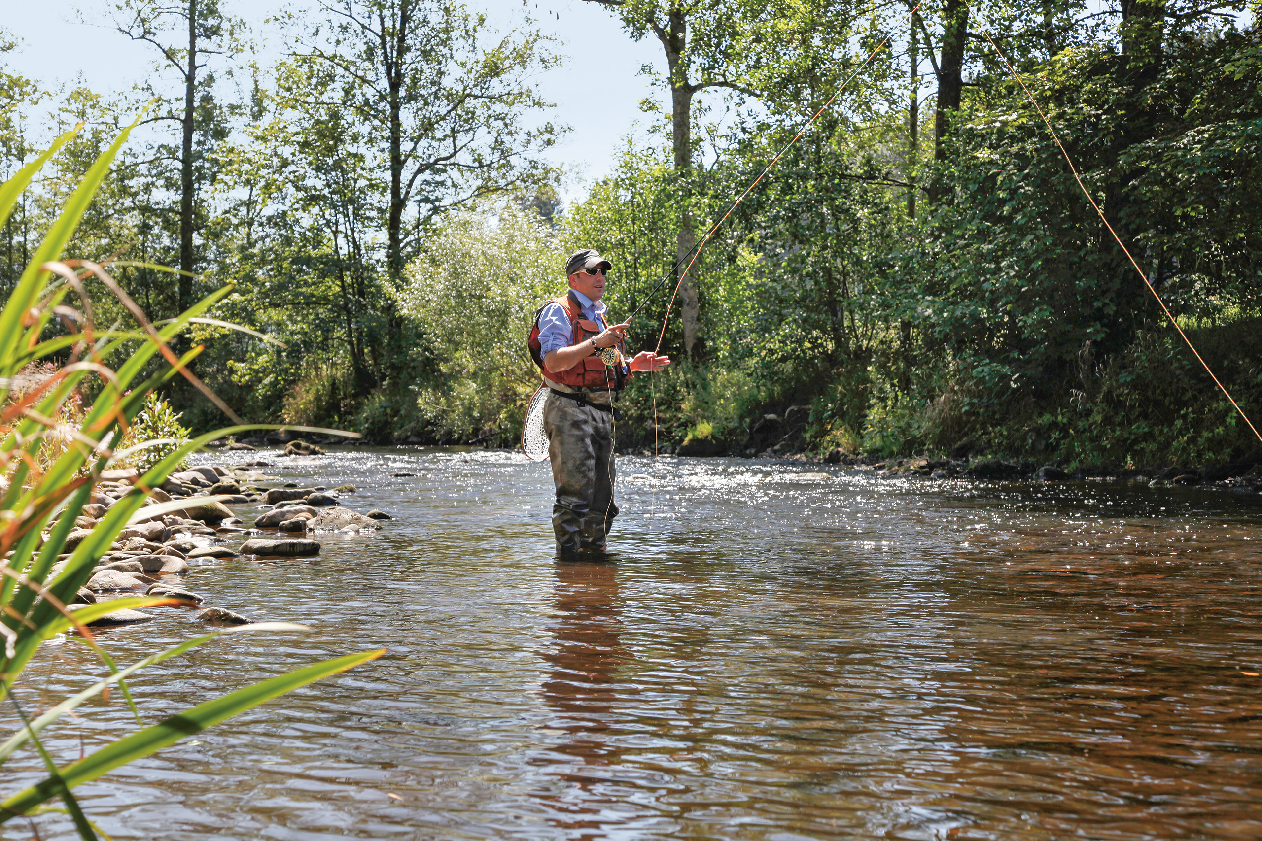 Ein Angler steht in einem Fluss im Luxushotel Schwarzwald und angelt