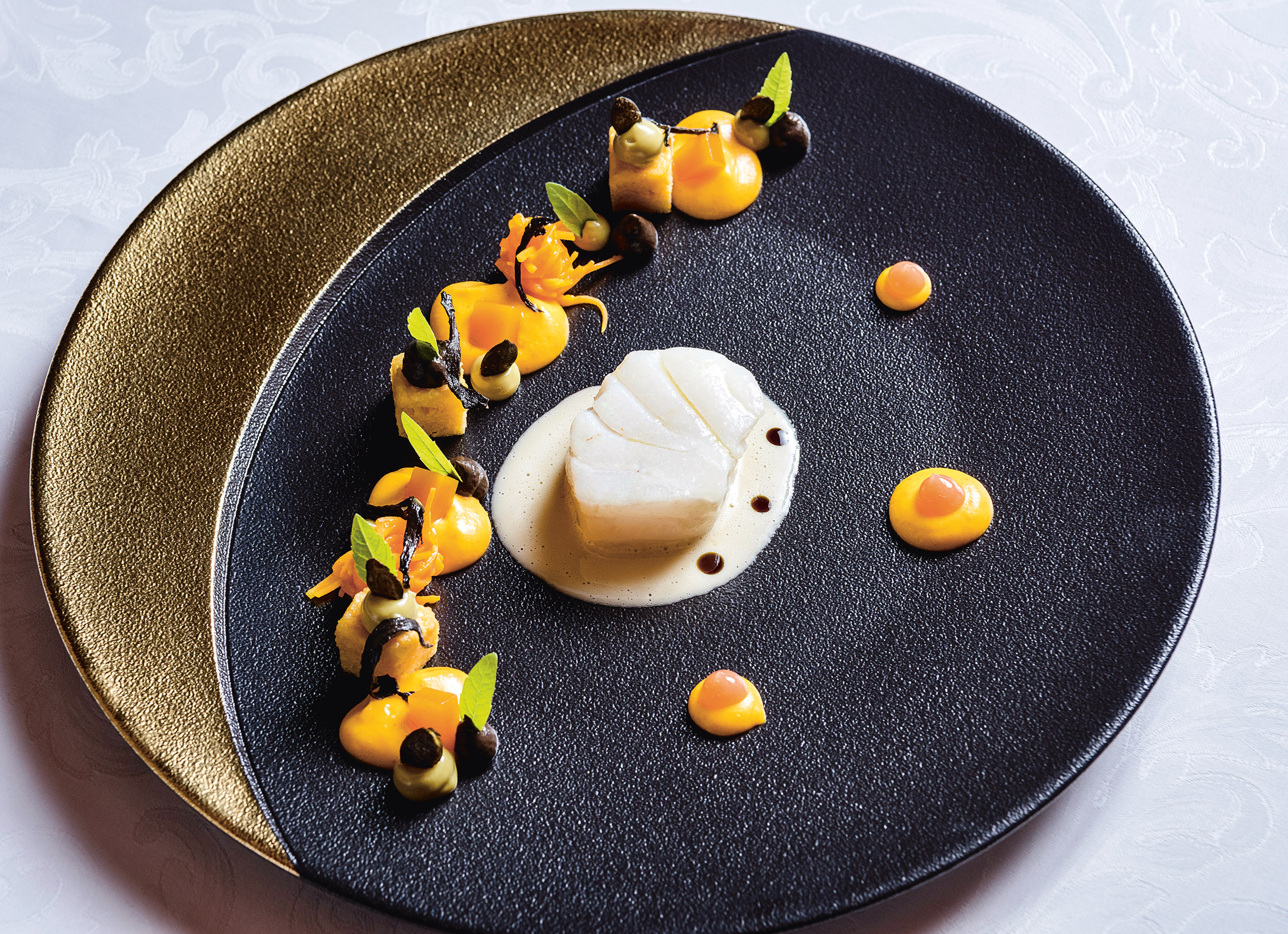 Schön angerichtete Häppchen auf einem schwarz/goldenen Teller